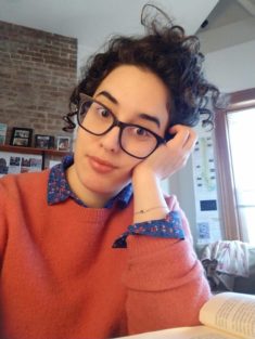 Cihan (read Jehan), a 35-year old woman with curly dark brown hair, prominent eyebrows and light wheat colored skin sits at her desk, wearing a pink sweater and glasses and resting her head on her left hand. She looks like many other people with roots in lands bordering the Mediterranean sea.